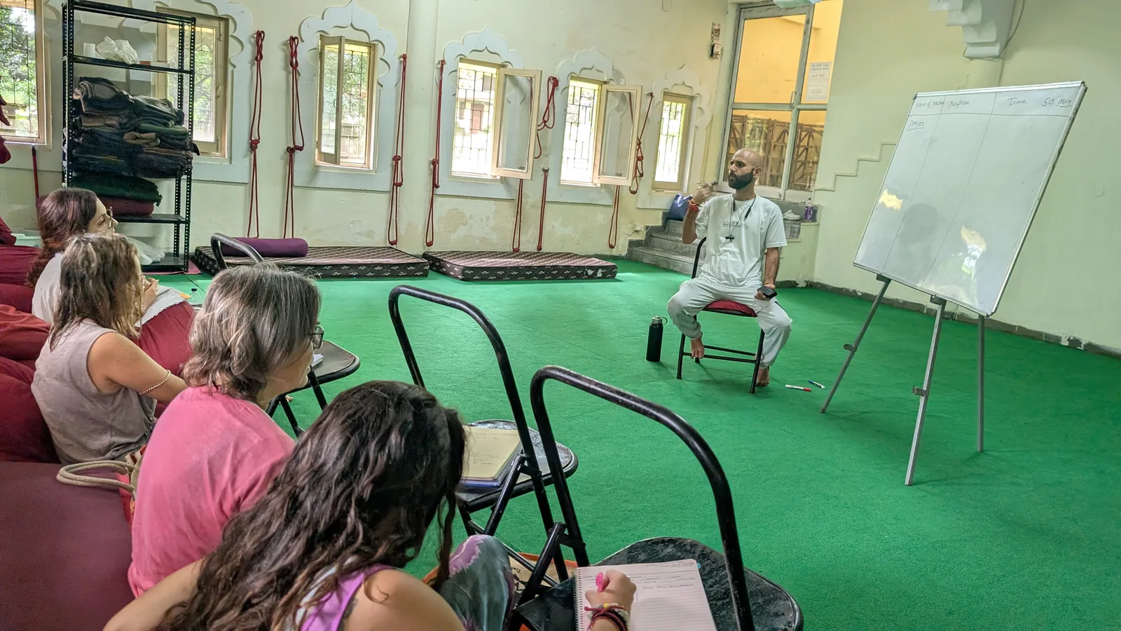Students learning yoga philosophy in a small-group classroom in Rishikesh